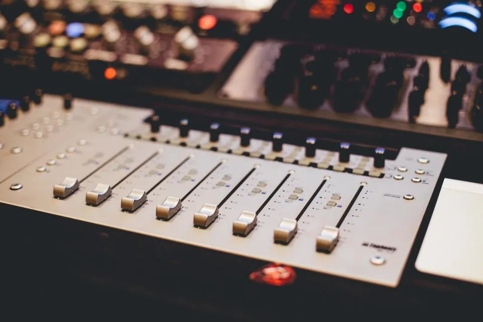 Faders on a studio mixing desk lit by warm control lights
